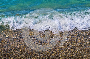 Foamy wave on pebble beach