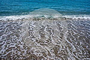 Foamy wave reaching the calm beach. Front view