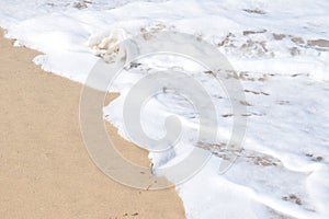 Foamy waves break softly on a pristine sandy beach