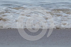 foamy waves on sand at the beach