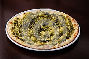 Focaccia with cheese and pesto on white dish on a dark wooden table