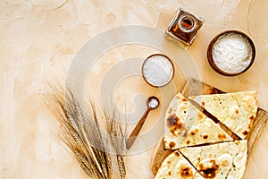 Focaccia ingredients. Wheat ears, flour, oil near bread on beige background top-down copy space