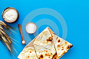 Focaccia ingredients. Wheat ears, flour, oil near bread on blue background top-down copy space