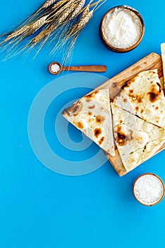 Focaccia ingredients. Wheat ears, flour, oil near bread on blue background top-down copy space