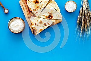 Focaccia ingredients. Wheat ears, flour, oil near bread on blue background top-down copy space