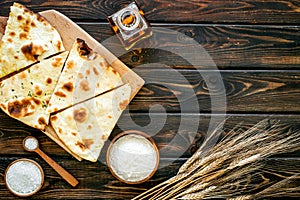 Focaccia ingredients. Wheat ears, flour, oil near bread on dark wooden background top-down copy space