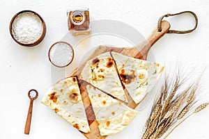 Focaccia ingredients. Wheat ears, flour, oil near bread on white background top-down