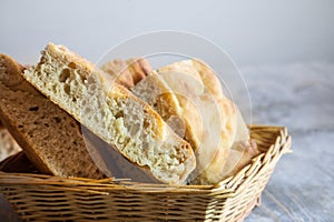 Italian bread of Focaccia Genovese type on display on a basket on a wooden table, sliced in squared pieces. photo