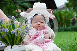 Focus at Asian newborn baby girl with costumes little sheep in the garden and mother is holding her.