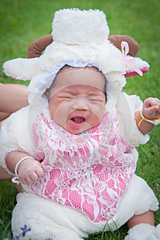 Focus at Asian newborn baby girl with costumes little sheep in the garden and mother is holding her.