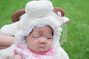 Focus at Asian newborn baby girl with costumes little sheep in the garden and mother is holding her.