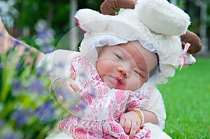 Focus at Asian newborn baby girl with costumes little sheep in the garden and mother is holding her.