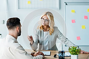 Focus of attractive blonde recruiter holding pen and looking at bearded man