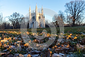 Focus on autumn leaves in the park, against the backdrop of the church in the Gothic style. View from below