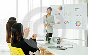 Focus beautiful Asian smiley businesswoman wearing suit, presenting business plan, coaching creative marketing idea in meeting,