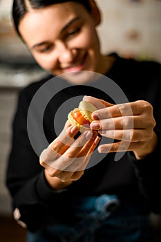 Focus on beige macaroon with pink cream in hands of female pastry chef