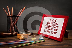 Focus on being productive instead of being busy. Picture frame with text on office table