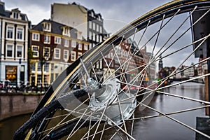 Selective focus on bicycle wheel with water drops with colorful buildings in the background blur in Amsterdam NETHERLANDS