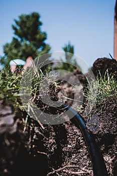 Focus on a black 1 inch sprinkler plastic water line laid in a shallow trench