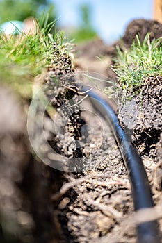 Focus on a black 1 inch sprinkler plastic water line laid in a shallow trench