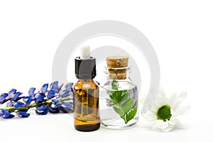 Focus of bottles with liquid near flowers isolated on white