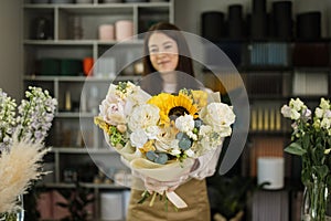 Focus on bouquet. Portrait of female florist in apron working in flower shop.