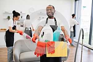 Focus on bucket with detergents in hands of African man cleaning worker.