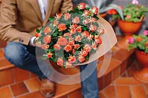 Focus on bunch of roses, folded in craft paper holded by man