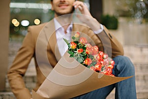 Focus on bunch of roses, folded in craft paper holded by man