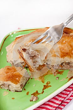 Focus on a burek on the fork with burek in the background