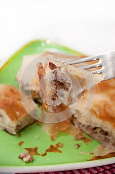 Focus on a burek on the fork with burek in the background