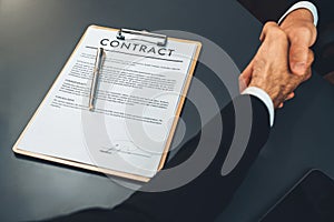 Focus business contract paper with blur background of handshake. Fervent