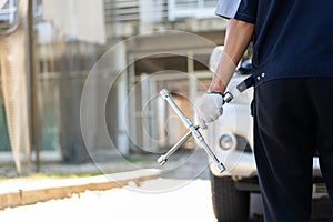 Focus car mechanic hand holding wrench for change the wheel on a broken car, uses tools or equipment, tries to solve problems by