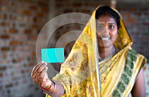 Focus on card, young indian daily wager woman showing green card by looking at camera - concept of job card