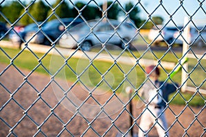 Focus on chain link fence behind youth t-ball baseball batter