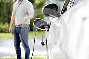 Focus charging EV car with blurred background of man standing at progressive EV.