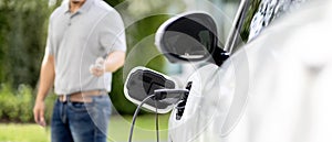 Focus charging EV car with blurred background of man standing at progressive EV.