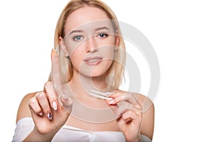 Focus on contact lens on finger of young woman. Young woman holding contact lens on finger in front of her face. Woman