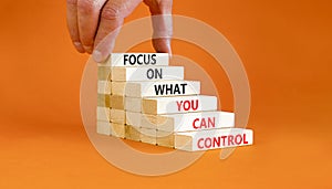 Focus on control symbol. Concept words Focus on what you can control on wooden block. Beautiful orange table orange background.