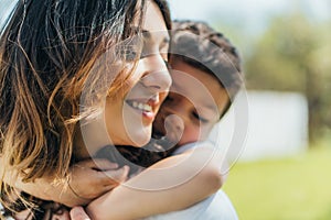 Focus of cute boy hugging happy mother