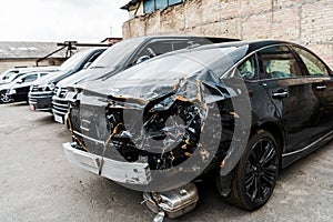 Focus of damaged black vehicle after car accident near modern automobiles