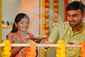 focus on daughter, Happy father arranging diya lamps on balcony with supportive daughter at home for diwali festival photo