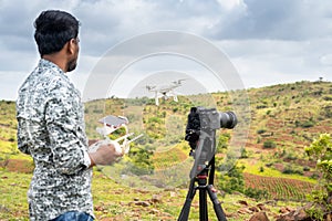Focus on drone, Young videographer filming video by controlling drone using remote controller - concept of professional drone