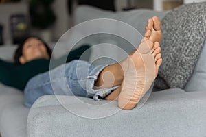 Focus on feet of young woman relaxing on couch barefoot