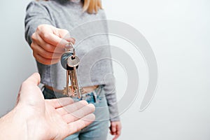 Focus on female hand holding house keys. Woman realtor giving bunch to new happy owner of property. Holding in hands house and