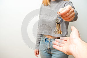 Focus on female hand holding house keys. Woman realtor giving bunch to new happy owner of property. Holding in hands house and