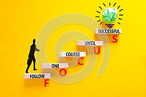 FOCUS follow one course until successful symbol. Concept words FOCUS follow one course until successful on wood block. Yellow