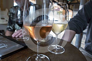 focus on a glass of rose wine and white wine at a table where friends and family have gathered for wine tastings