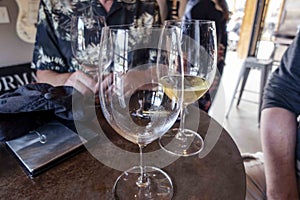Focus on a glass of rose wine and white wine at a table where friends and family have gathered for wine tastings