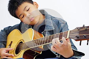 Focus on the hands of the child or teenager playing acoustic guitar on white background. Learning and relax concept